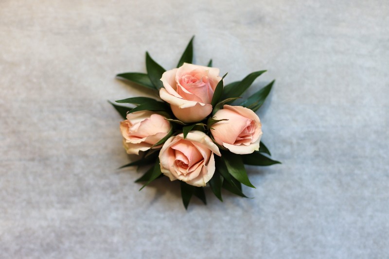 Pink rose corsage with dark green leaves by Studley Flower Gardens