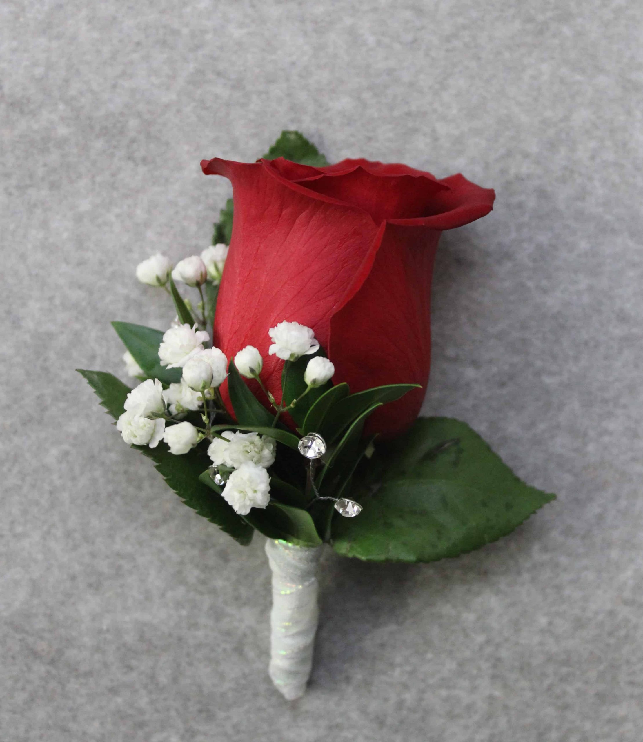 Bold rose boutonniere with greenery accents by Studley Flower Gardens