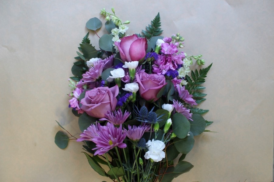 Cosmic lilac wrapped bouquet with lavender and purple blooms by Studley Flower Gardens