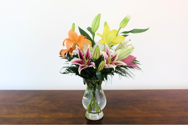 Lily bouquet with vibrant lilies in a glass vase by Studley Flower Gardens