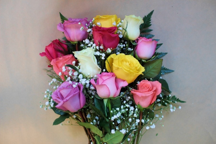 Mixed roses wrapped bouquet with pastel blooms and greenery by Studley Flower Gardens