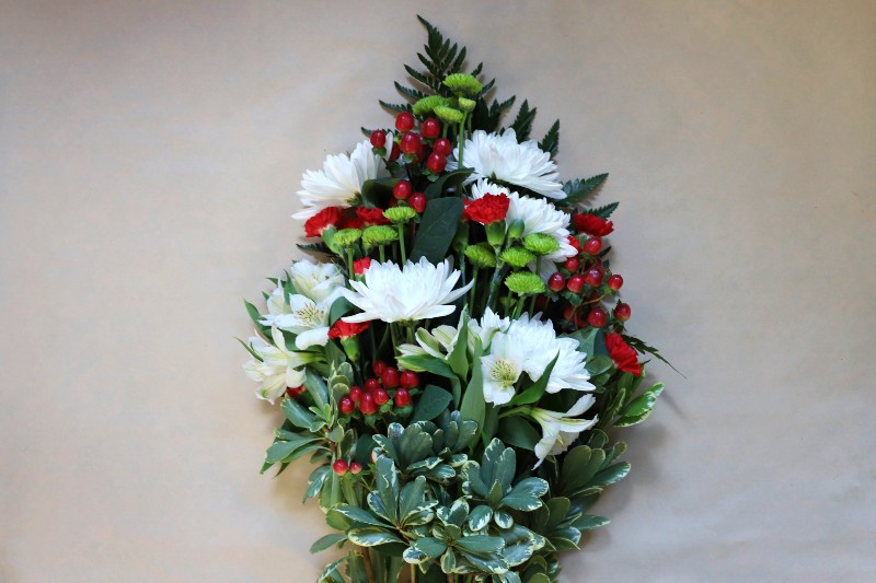 Ruby Crystal wrapped bouquet with red, white, and green blooms by Studley Flower Gardens