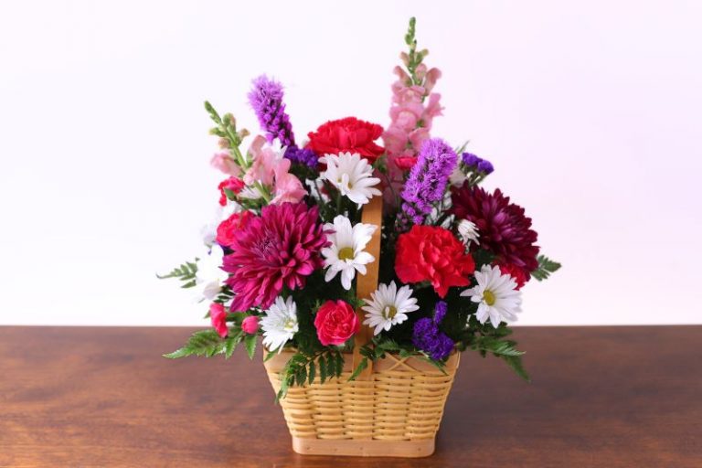 Salmon Falls Bouquet with pink and purple carnations in wicker basket by Studley Flower Gardens